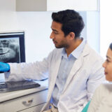 Dentist reviewing a dental X-ray with a patient before discussing root canal treatment